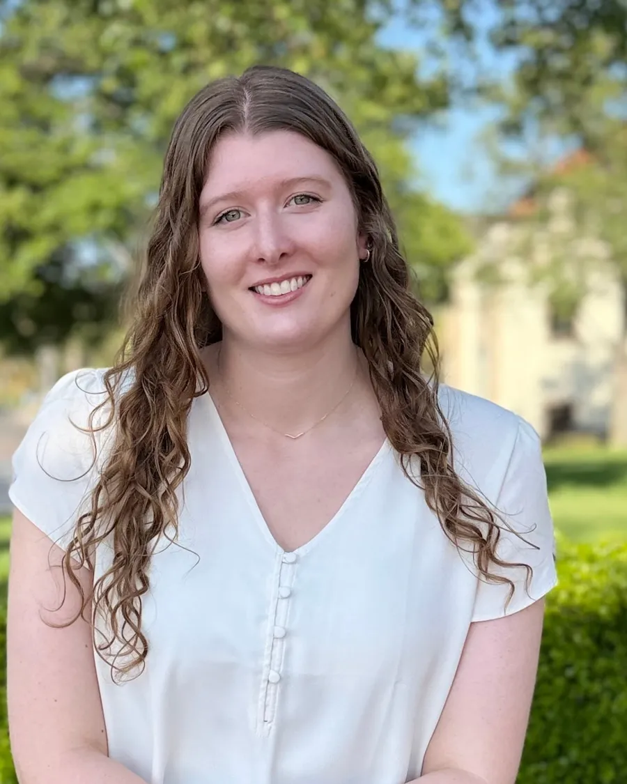Sarah Hoogerwerf seated on a bench outdoors, smiling at the camera